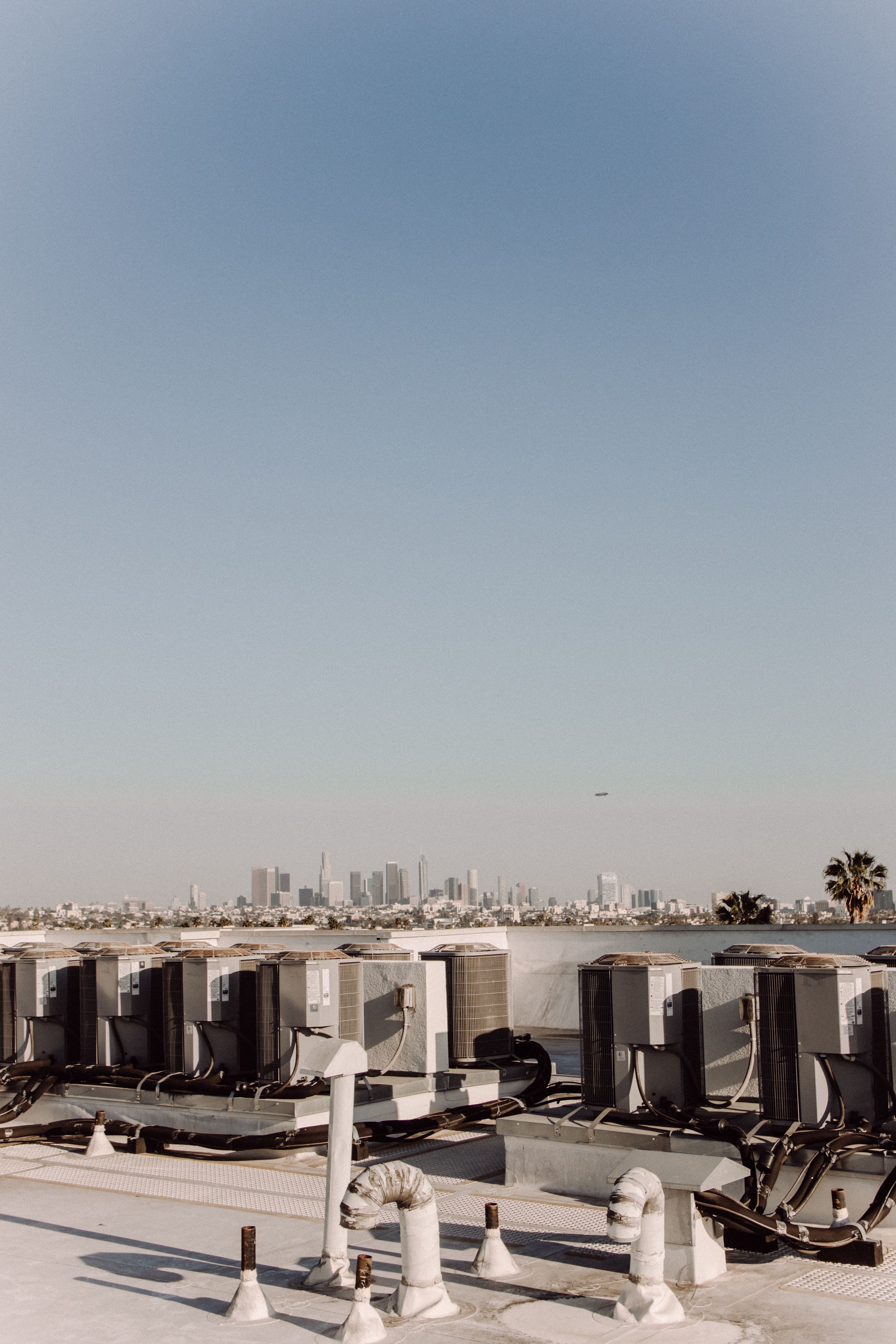 Rows of rooftop HVAC units with a city skyline behind